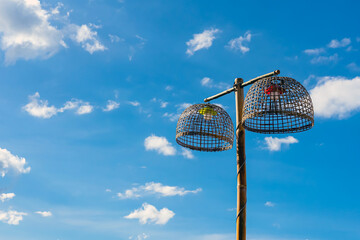 Lamps made from chicken coop with blue sky. Handmade bamboo lighting. Lamp holder from woven bamboo basket. Traditional handmade bamboo chicken coops repurposed as creative outdoor hanging lamps.