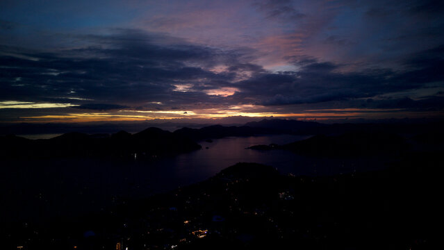 High altitude night aerial panoramic view of Coron Bay islands and coastal town lights in Palawan, Philippines, during blue hour twilight under dramatic cloudy sky over calm sea. - Powered by Adobe