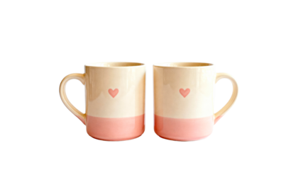 Two matching ceramic coffee mugs with small heart prints, perfect for a couple's breakfast, isolated on white
