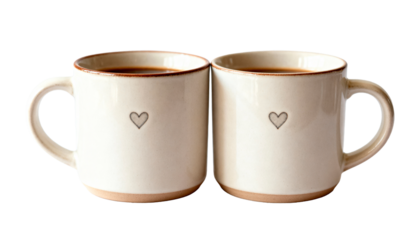 Two matching ceramic coffee mugs with small heart prints, symbolizing a couple's breakfast or romantic morning, isolated on a clean white background.