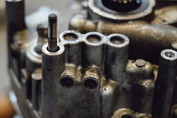 Disassembled old car gearbox with gears and tools on a workbench in an auto service garage. Repair, maintenance, and replacement of worn mechanical transmission parts in a vehicle.