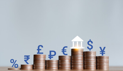 Stacked coins with wooden blocks with world currency symbols representing financial growth, exchange rates, investment, foreign exchange trading and international economy concept.