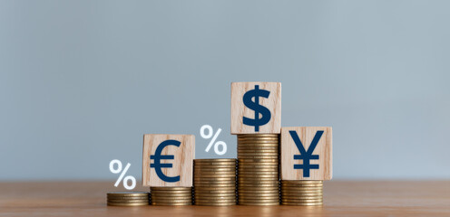 Stacked coins with wooden blocks with world currency symbols representing financial growth, exchange rates, investment, foreign exchange trading and international economy concept.