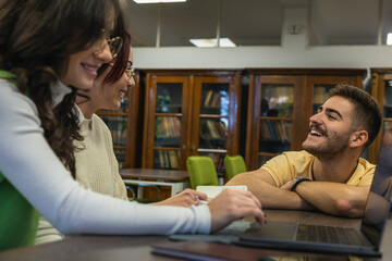 Students collaborating around a laptop in the campus reading room
