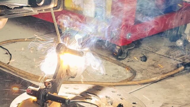Intense industrial welding with bright electric sparks and smoke on metal