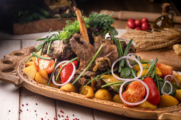 Traditional Kazakh syrne made with tender lamb, potatoes, tomatoes, onions and herbs served on a wooden platter