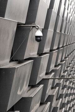 This image captures a surveillance camera mounted on a contemporary architectural facade, symbolizing security and oversight in modern urban environments.