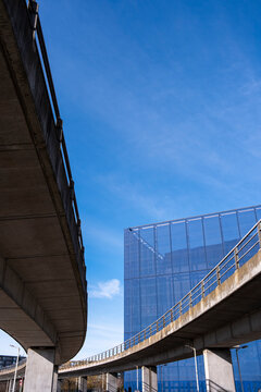 The dynamic interplay of curved overpasses leads the eye towards a sleek glass building, showcasing modern architecture and efficient urban design against a clear sky.