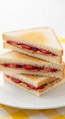 Stack of three toasted triangular sandwiches filled with peanut butter and jelly, representing childhood comfort and simple pleasure, perfect snack
