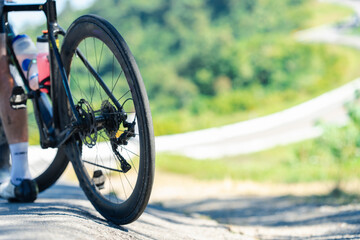 Fototapeta premium A cyclist's bike tire on a winding road, surrounded by lush greenery, capturing a moment of outdoor adventure and fitness.