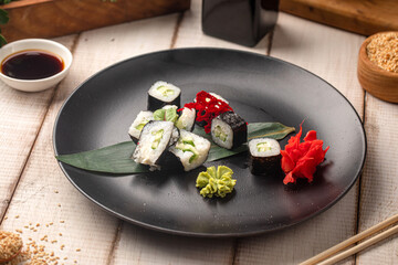 Vegetarian sushi rolls with cucumber served on a black plate with ginger wasabi and soy sauce © Hihitetlin