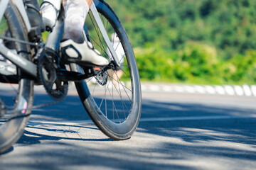 A close-up of a cyclist's bike wheel on a smooth road with greenery in the background, capturing the essence of outdoor cycling.