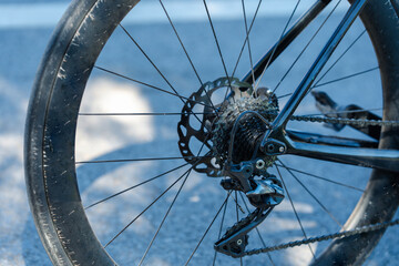 Close-up of a bicycle rear wheel, showcasing the intricate details of the gear system and spokes against a blurred background.