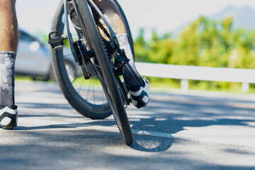 A cyclist experiences a flat tire on a sunny road, showcasing the struggle of cycling amidst beautiful surroundings.