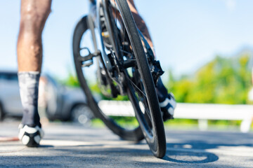 A cyclist focuses on the road ahead, showcasing the wheel and leg in motion against a vibrant background.