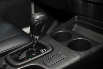 Automatic transmission gear with leather of luxury car on glossy black console interior detail. concept transport travel. 	