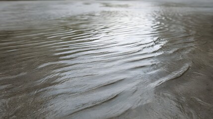 Close up of wet sand with intricate ripple patterns formed by flowing water