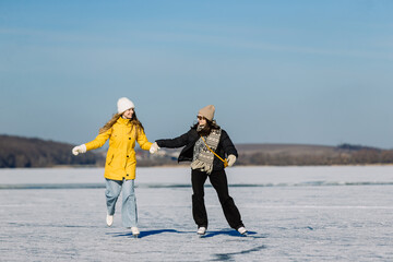Women ice skating on frozen lake, holding hands