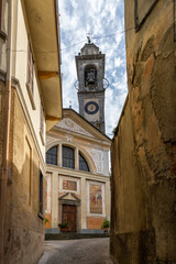 Historic bell tower and facade of the Church of Sant'Eusebio in the center of Pasturo, Italy. A striking glimpse between the village buildings.