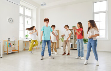 Fototapeta premium Group of pupils or students spending leisure time together during a break in the school classroom, playing and enjoying themselves. Fun and happiness of children relaxing together.