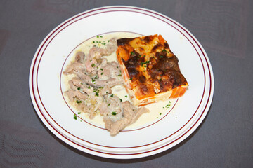 creamy veal ragout with potato and carrot gratin on a white plate