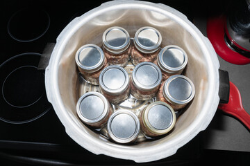 Top view of ten, pint jars filled with pork sausage in a canner on a stove