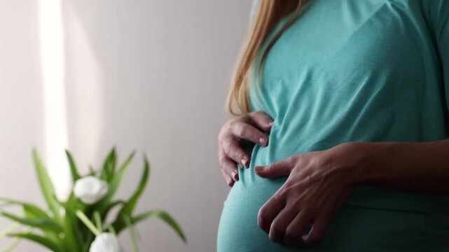 Pregnant woman scratching and after gently petting her big belly. Skin stretching during pregnancy. 4K
