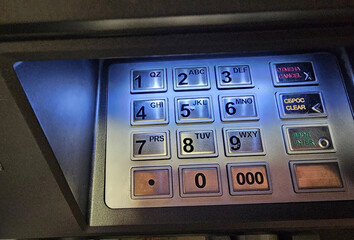 Close up of ATM keypad with illuminated buttons used for entering numbers and commands in banking transaction concept