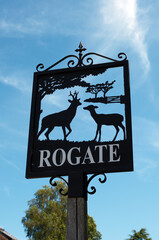 Ornate Black Silhouette of Deer on Rogate Village Welcome Sign Against Blue Sky
