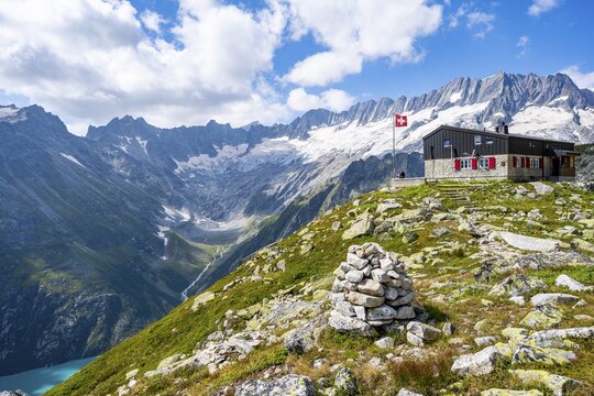 Mountain hut Bergseeh&uuml;tte with Swiss flag in picturesque mountain landscape, view of Damma Glacier and Dammastock, G&ouml;scheneralp, Canton of Uri, Switzerland