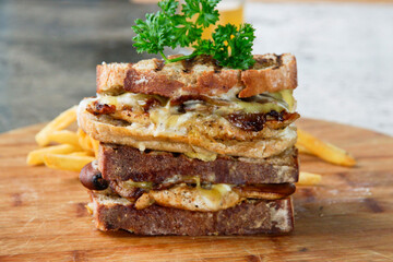 Close-up of a stacked grilled chicken sandwich with melted cheese, caramelized onions, and rustic bread on a wooden board. Perfect for food marketing, restaurant menus, and culinary promotions.