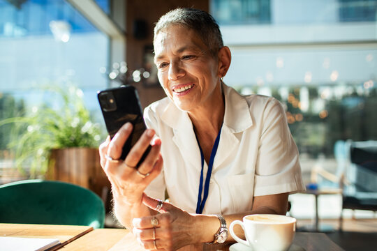 Senior woman smiling while using smartphone in cafe