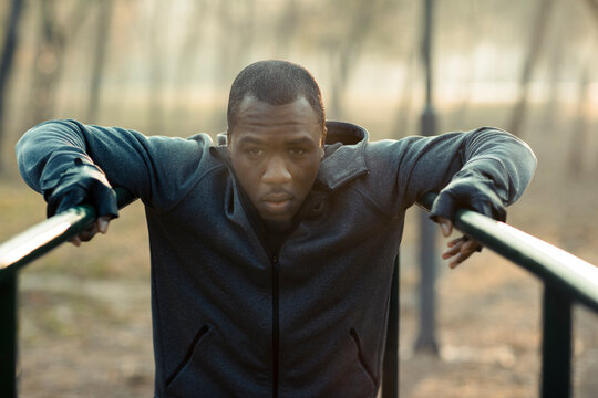 Young adult man focused on calisthenics workout at outdoor park