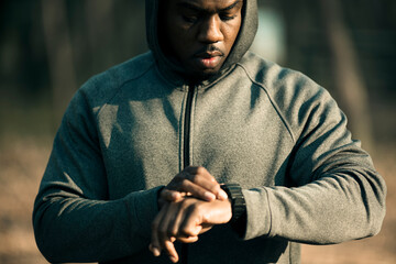 Young adult man checking smartwatch in park, focused