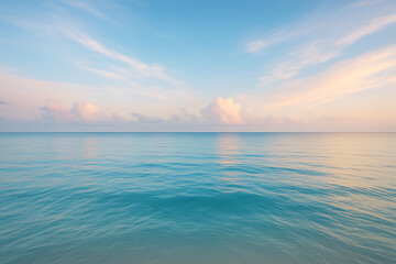 Obraz premium Tranquil ocean water horizon under pastel colored sky at dawn with soft ripples and clouds