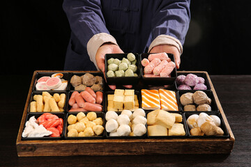 Chef Holding Wide Variety of Hot Pot Ingredients Including Meatballs and Beef in Wooden Tray for Asian Cooking