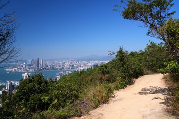 Naklejka premium Hong Kong cityscape with Victoria Harbour. Sunny day city view from Braemar Hill hiking trail.