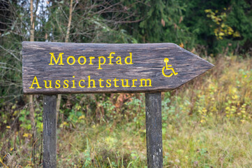 Information sign with the German words Moor path and observation tower and the handicapped accessible sign