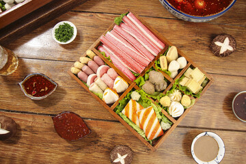 Hot Pot Shabu Shabu Ingredients with Meatballs and Spicy Sauces - Wide Variety of Fresh Asian Food on Wooden Table