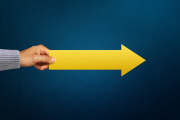 A man hold carry yellow arrow pointing to the side. represents development path direction success statistics growth aim achievement