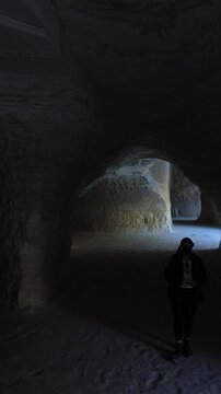 Female tourist silhouette walking inside rocky cave passage in chalk mines in Mexico zoom in camera movement