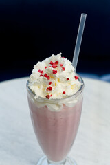 Strawberry milkshake with whipped cream and freeze-dried berries in a glass.