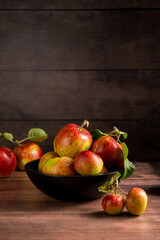 Freshly picked red apples in a bowl, rustic wooden background