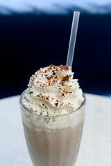Chocolate milkshake with whipped cream and cocoa chips in a tall glass.