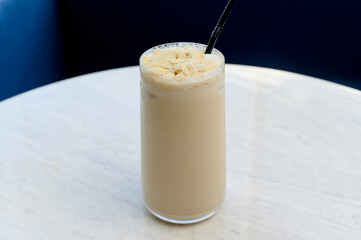 Tall glass of iced latte with almond flakes