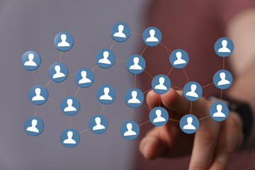Abstract image of a network concept. Human hand points to connected user icons representing teamwork and commun