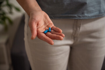 Woman holding blue pills in hand. Health care, dietary supplements, treatment of depression and diseases