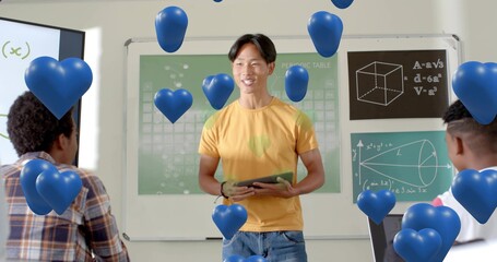 Presenting pupil wearing yellow tee, jeans holding tablet in class with periodic table, blue hearts © vectorfusionart