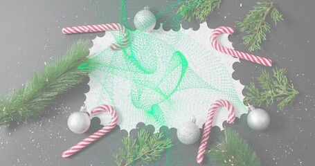 Showing white scalloped card with green mesh on gray table, candycanes, baubles, evergreen, snow