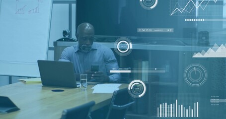 Checking man in light-blue shirt scrolling phone and reviewing laptop in meeting room with papers